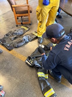 A group of firefighters collecting smoke residue samples on turnout gear using cleanroom wipes for a research project.