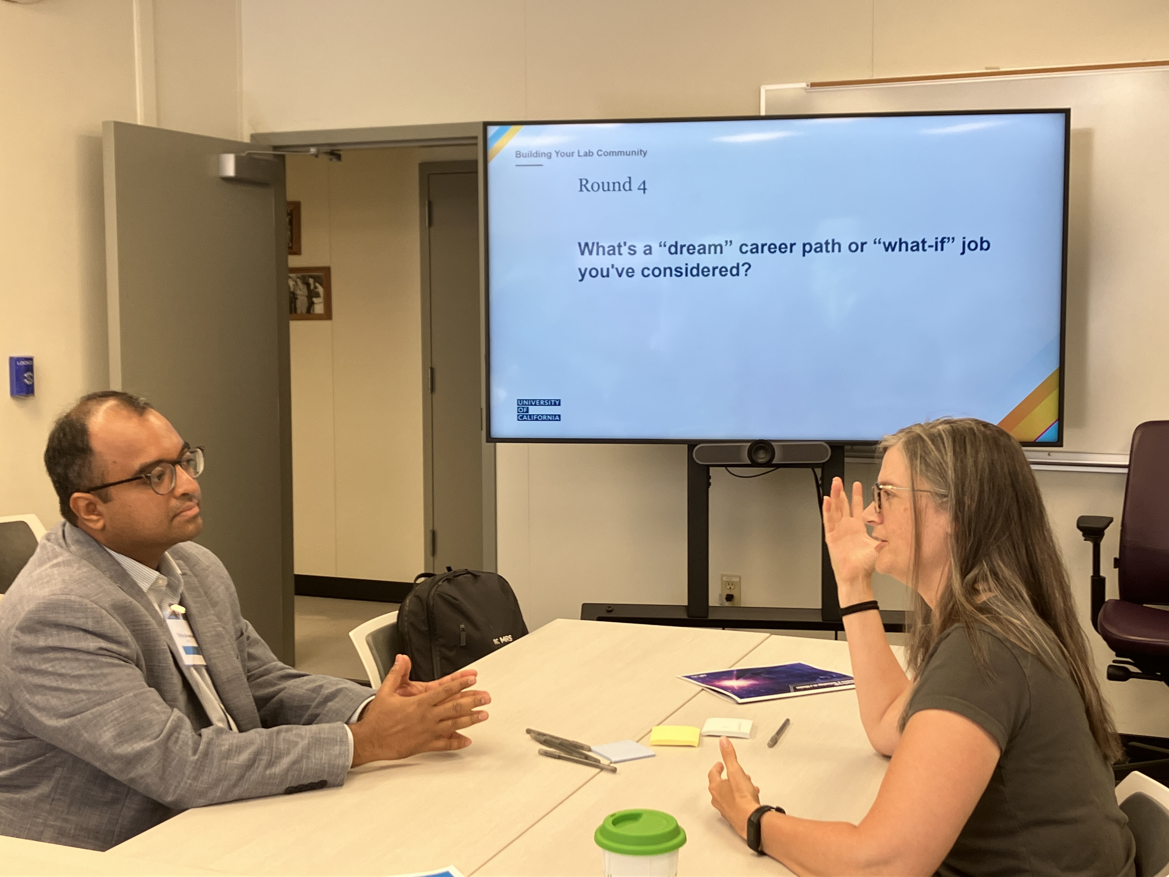 Two mentors seated at a table discussing.