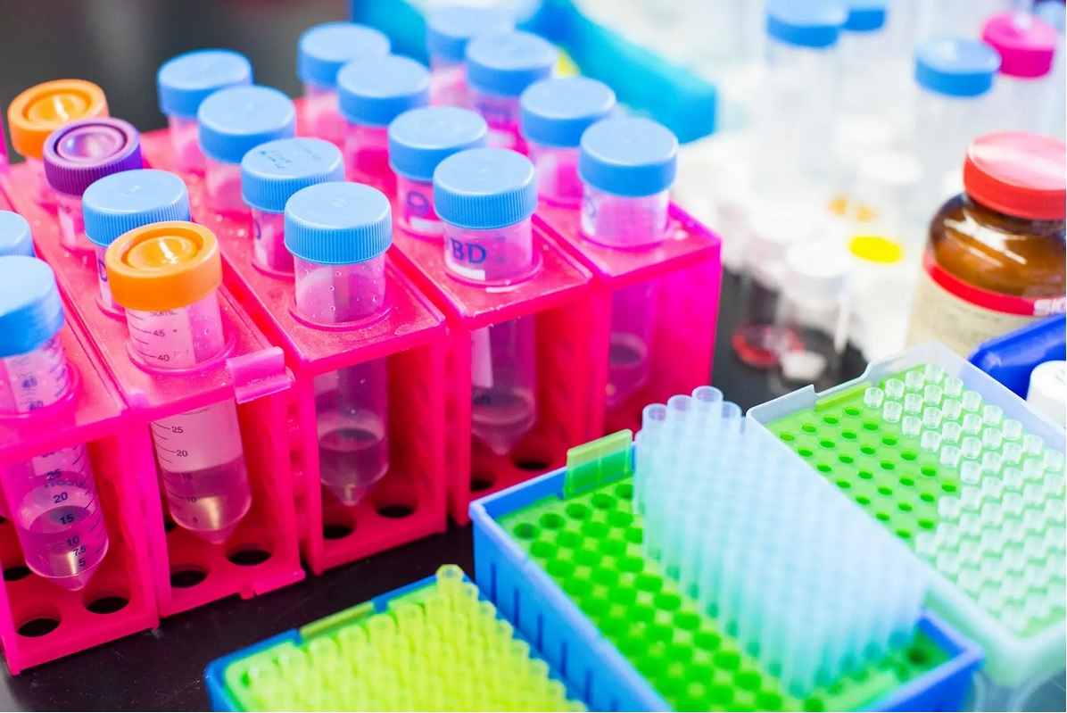 Close-up of a lab table on which are racks holding capped test tubes and pipette tips.