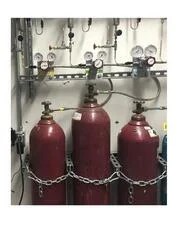 Three closed red gas cylinders with a safety chain fastening them to their mounting rack.